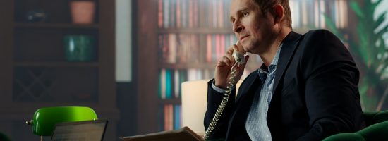 Skilled intelligence agent on a secure landline phone call discussing confidential information and doing background check on a suspect. Untraceable disposable number in espionage. Camera B.